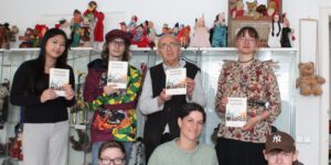 Molla Demirel mit Jugendgruppe hält das neu erschienene Buch „Demokratie in der pluralen Gesellschaft“ (Foto: Radio Kaktus Münster e.V. / Greta Börding)